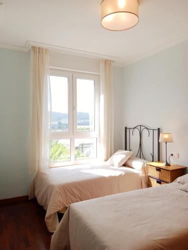 a white bedroom with two beds and a window at El Mirador 2 in Viveiro
