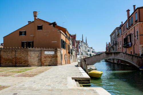 a canal with a bridge and a yellow boat at Ca' Tintoretto in Venice