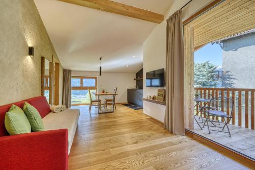 sala de estar con sofá rojo y balcón en Pröfinghof - Urlaub auf dem Biobauernhof, en Parcines