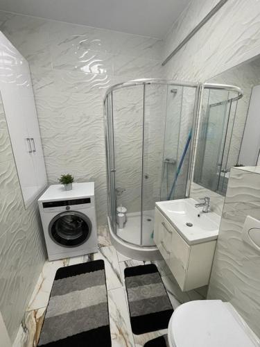a bathroom with a shower and a washing machine at CONFORT' by J in Iaşi