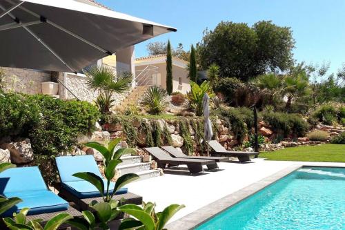 a swimming pool with lounge chairs and a house at Villa Girassol met zwembad in Alcantarilha
