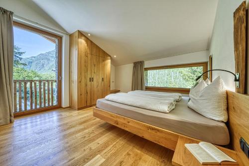 sypialnia z dużym łóżkiem i dużym oknem w obiekcie Pröfinghof - Urlaub auf dem Biobauernhof w mieście Parcines