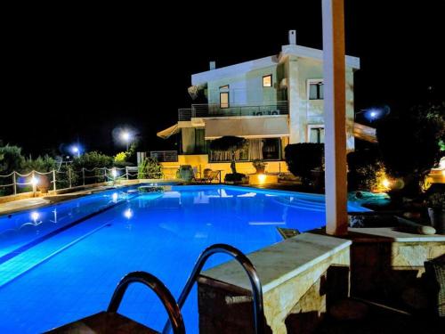 a swimming pool in front of a house at night at Summer Villa Lagonissi in Lagonissi