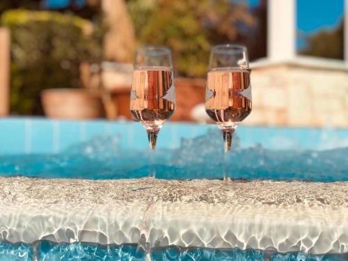 dos copas de vino sentadas en el borde de una piscina en Summer Villa Lagonissi en Lagonissi