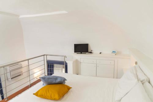 a white bedroom with a yellow pillow on a bed at Cala Moresca Apartments in Bacoli
