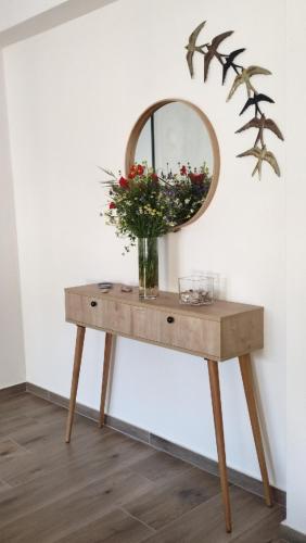 a table with a mirror and a vase of flowers on it at To Helidoni Apartment & Gardens in Nikiti