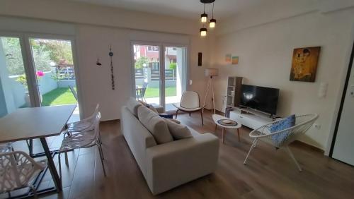 a living room with a white couch and a tv at To Helidoni Apartment & Gardens in Nikiti