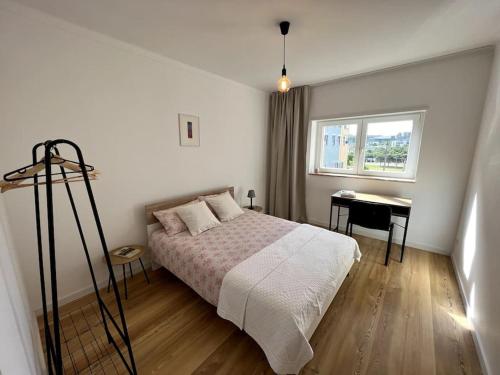 een slaapkamer met een bed, een bureau en een raam bij Ambiente moderno com bom gosto in Coimbra