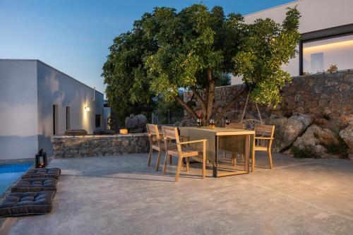a dining area with a table and chairs and a tree at Casatino Villas in Kalianeika