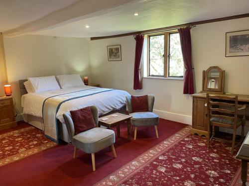 a bedroom with a bed and two chairs and a desk at Gilberts End Farm in Great Malvern