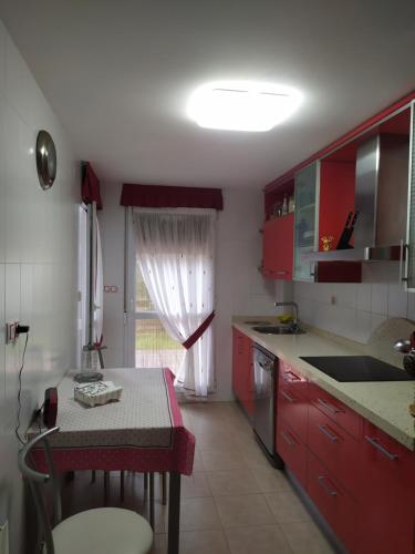 une cuisine avec des placards rouges, une table et une fenêtre dans l'établissement Apartamento Casa Labaro, junto al Parque de Cabárceno, à Arenal