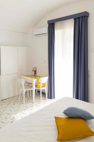 a bedroom with a white bed with a table and chairs at Cala Moresca Apartments in Bacoli