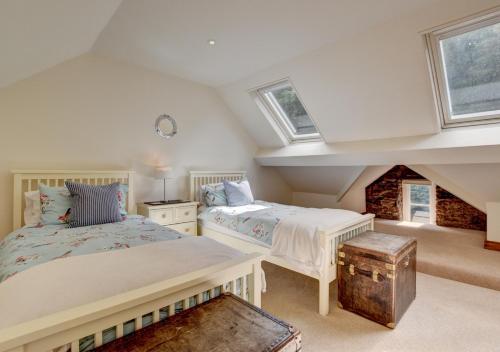 twee bedden in een zolderkamer met twee ramen bij River Cottage in Lynmouth