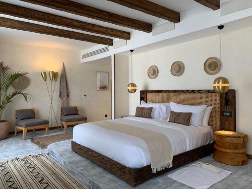 1 Schlafzimmer mit einem großen Bett und 2 Stühlen in der Unterkunft Le Sidi - A TLT Signature Hotel in El-Alamein