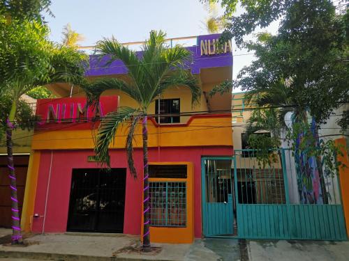 a colorful building with a palm tree in front of it at Numa Hotel Boutique in Playa del Carmen