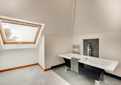 een witte badkamer met een wastafel en een raam bij Sanderling in Braunton