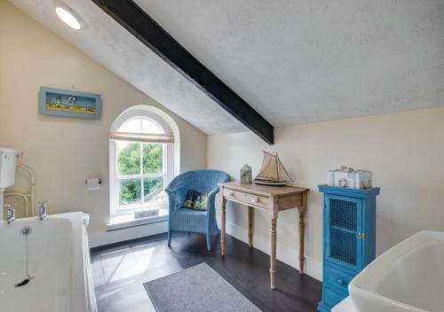 a bathroom with a table and a blue chair and a desk at Boslandew House in Paul