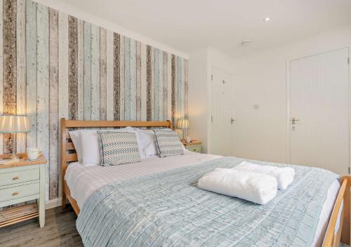a bedroom with a large bed with a wooden headboard at The Beach House - Porthcurno in Saint Levan