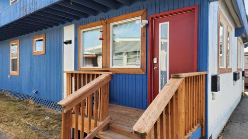 Nightshade BnB في أنكوراج: منزل ازرق مع شرفة خشبية وباب احمر