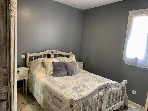 a bedroom with a bed with gray walls and a window at Le Marcelou in Entraigues-sur-la-Sorgue