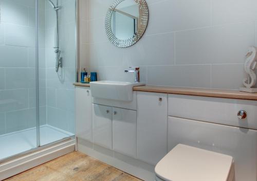 a white bathroom with a sink and a shower at Sea Spray in Westward Ho