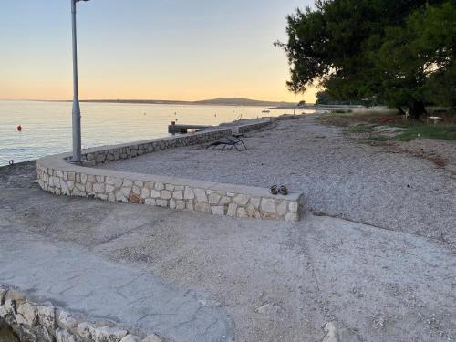 a bench on a beach next to a body of water at Villa Eugenia in Košljun