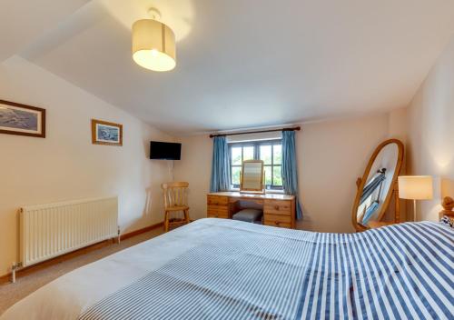 a bedroom with a bed and a desk and a window at Swallow Barton in Atherington