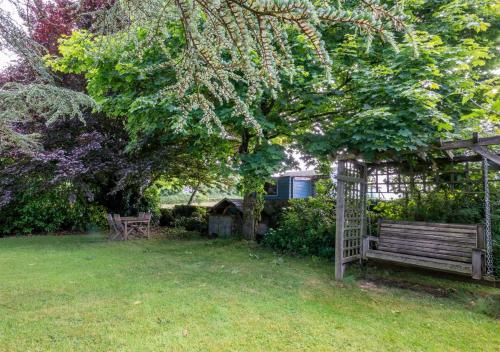 a garden with a bench and a gazebo at Swallow Barton in Atherington