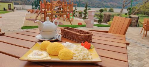 une assiette de nourriture sur une table avec une théière dans l'établissement Complex Turistic Cetatea Drencova, 