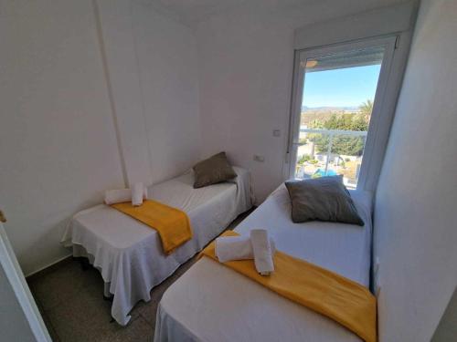 Duas camas num pequeno quarto com uma janela em V19 Ático con impresionantes vistas al mar B16 em Denia