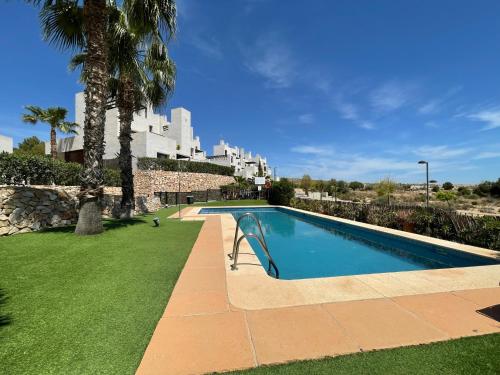 einen Pool in einem Garten mit Palmen und einem Gebäude in der Unterkunft Corvera Hills, Corvera Golf and country club in Corvera