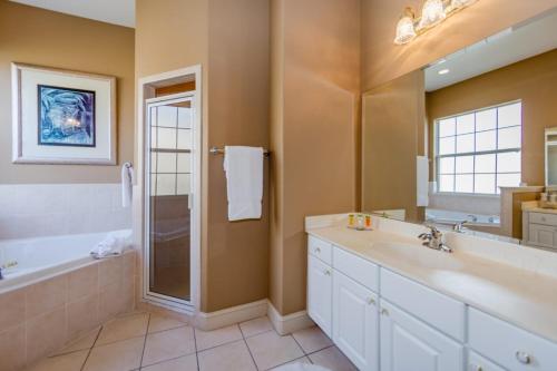 een badkamer met een bad, een wastafel en een douche bij Oasis Villa - Heated Pool And Spa Near Disney in Davenport