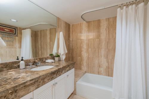 a bathroom with a sink and a tub and a shower at Royal Garden Waikiki - Wyndham Resort in Honolulu