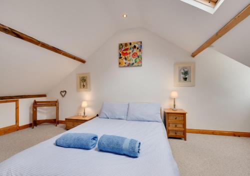 a bedroom with a bed with two blue pillows on it at Temperance Cottage in Braunton