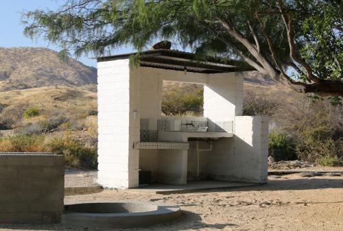 a small white building in the desert with a tree at Achab Camping Camp site in Usakos
