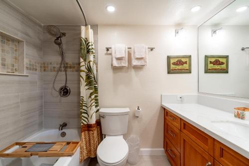 a bathroom with a tub and a toilet and a sink at Sunset Shores - Waialua Oceanfront Retreat in Waialua