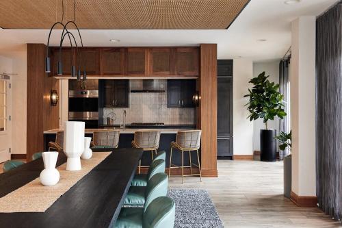 a kitchen with a long dining table with green chairs at Sentral Old Town in Scottsdale