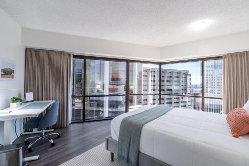 a hotel room with a bed and a desk and a window at Stunning Skyview, Pool, Fabulous Location! in Honolulu