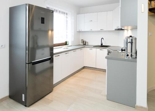 - un réfrigérateur en acier inoxydable dans une cuisine avec des placards blancs dans l'établissement Moody Hostel, à Mława