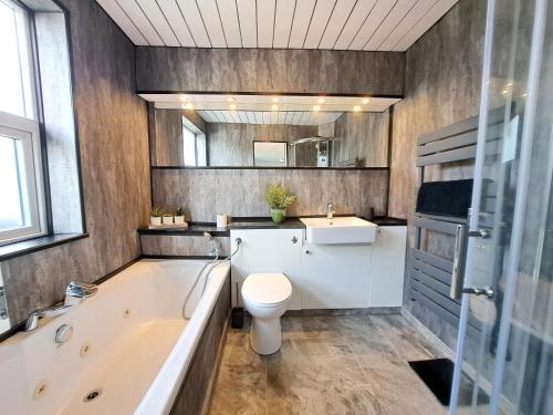 a bathroom with a tub and a toilet and a sink at Bright 3 Bed Apartment With Terrace, Free Parking On Premises in Watford