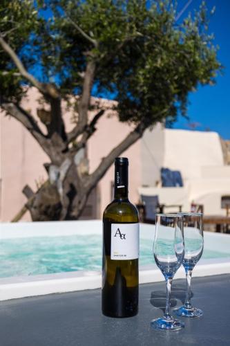 a bottle of wine and two wine glasses on a table at Elysian Elia Heritage in Oia