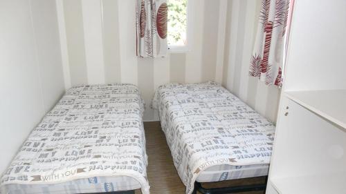 deux lits dans une petite pièce avec une fenêtre dans l'établissement Bungalow charmant Gastes piscine privée, à Gastes