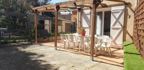 eine hölzerne Pergola mit einem Tisch und Stühlen auf einer Terrasse in der Unterkunft Location saisonnière in Coursan