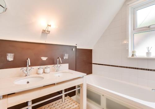 a bathroom with a sink and a bath tub and a window at Wisteria Cottage in Parkham