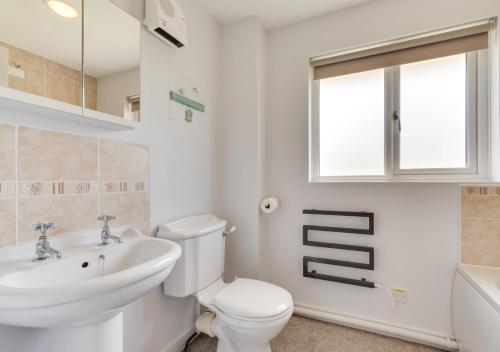a white bathroom with a sink and a toilet at Withyside in Croyde