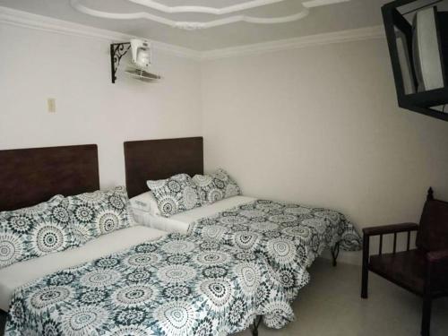 a bedroom with two beds and a chair at Hotel Central Johanna in Tuluá