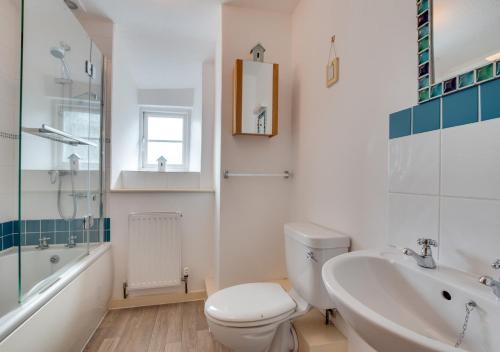 a bathroom with a toilet and a tub and a sink at Willow Cottage in Braunton