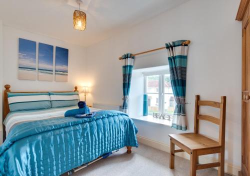 a bedroom with a bed and a chair and a window at Willow Cottage in Braunton