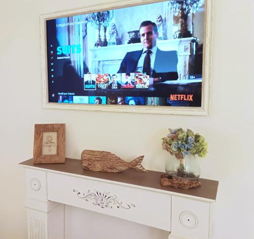 a tv hanging on a wall above a white table at Tulipano Bianco in Ostuni