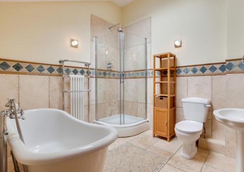 een badkamer met een bad, een toilet en een wastafel bij Wisteria Cottage in Great Torrington